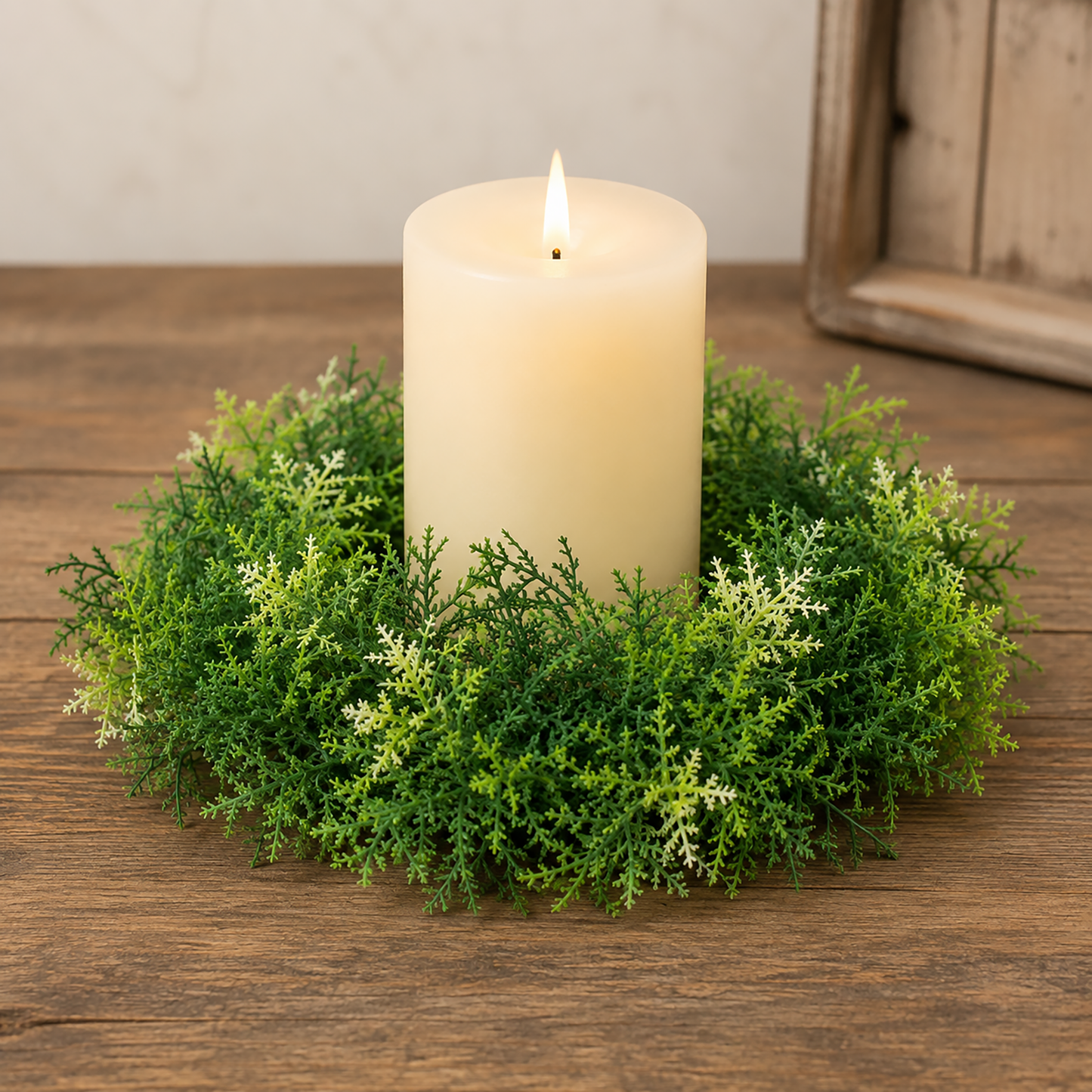 Forest moss candle ring with layered green foliage displayed around a cream pillar candle on a rustic wood tabletop