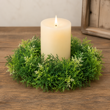 Forest moss candle ring with layered green foliage displayed around a cream pillar candle on a rustic wood tabletop