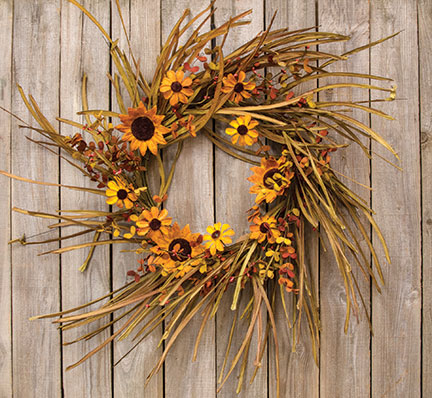 Round grassy wreath with large yellow sunflowers and fall leaves on a neutral background