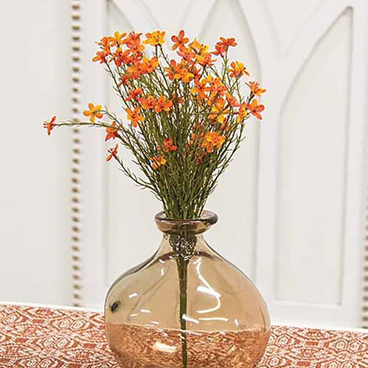 Glass vase with orange flowers on a patterned surface