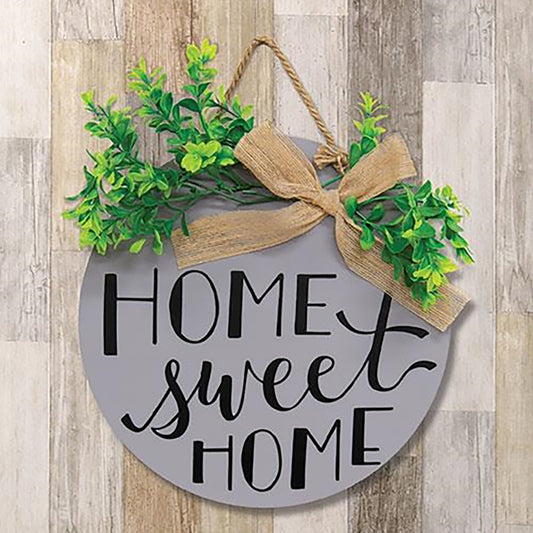 Round wood wall sign with “home sweet home” lettering, faux greenery, and burlap bow on blue background