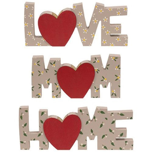 Full set of three floral wooden word signs displayed on a shelf with greenery