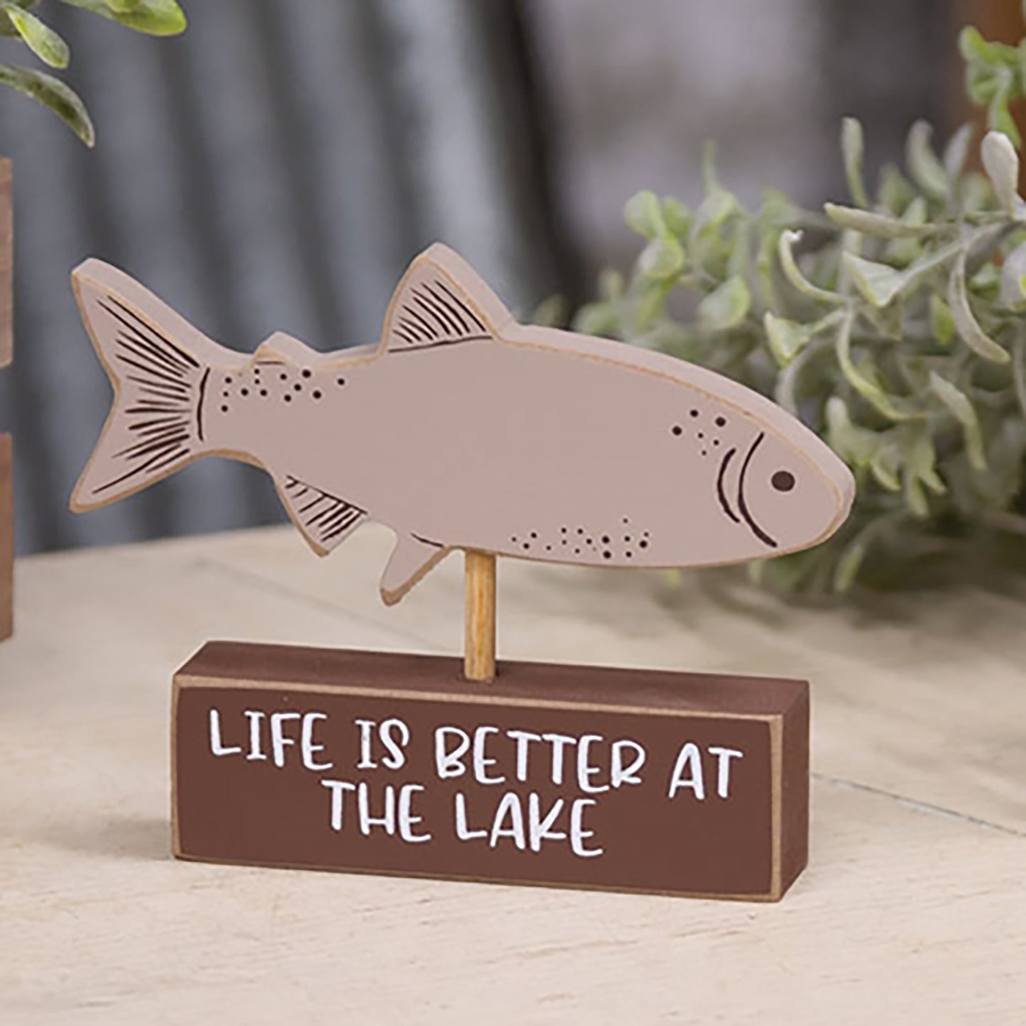Wooden taupe fish figurine mounted on brown block with “Life is Better at the Lake” text