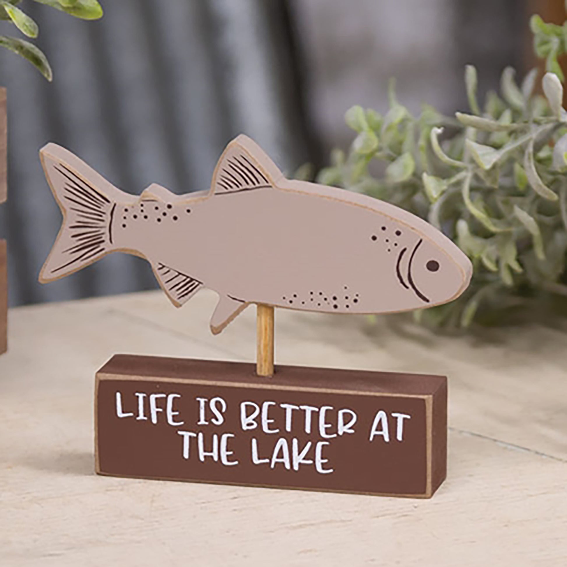Wooden taupe fish figurine mounted on brown block with “Life is Better at the Lake” text