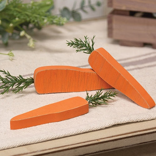 Set of three chunky wooden carrots with orange painted finish and green leafy tops