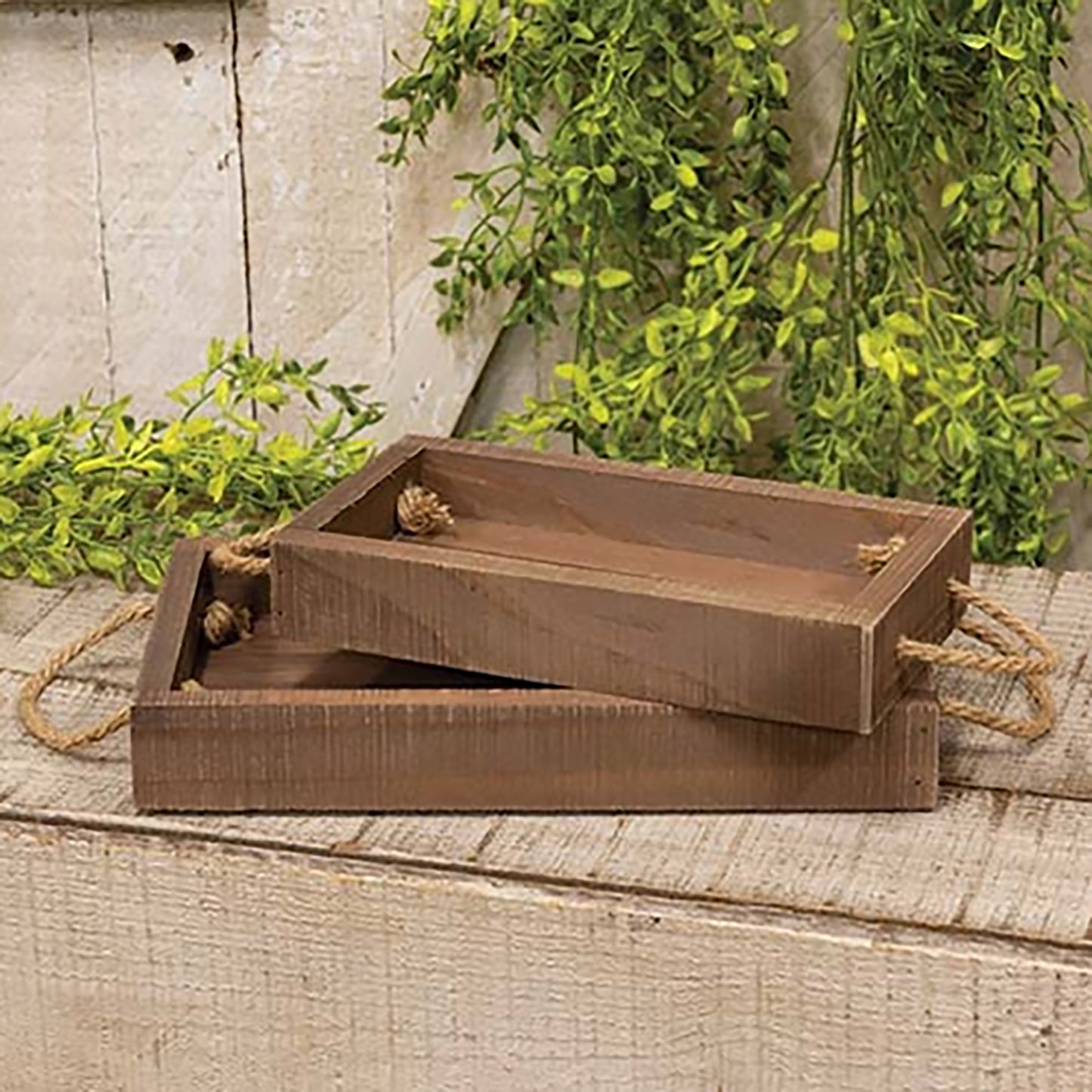Rustic stained wood nesting tray set with jute rope handles styled on farmhouse coffee table with seasonal decor