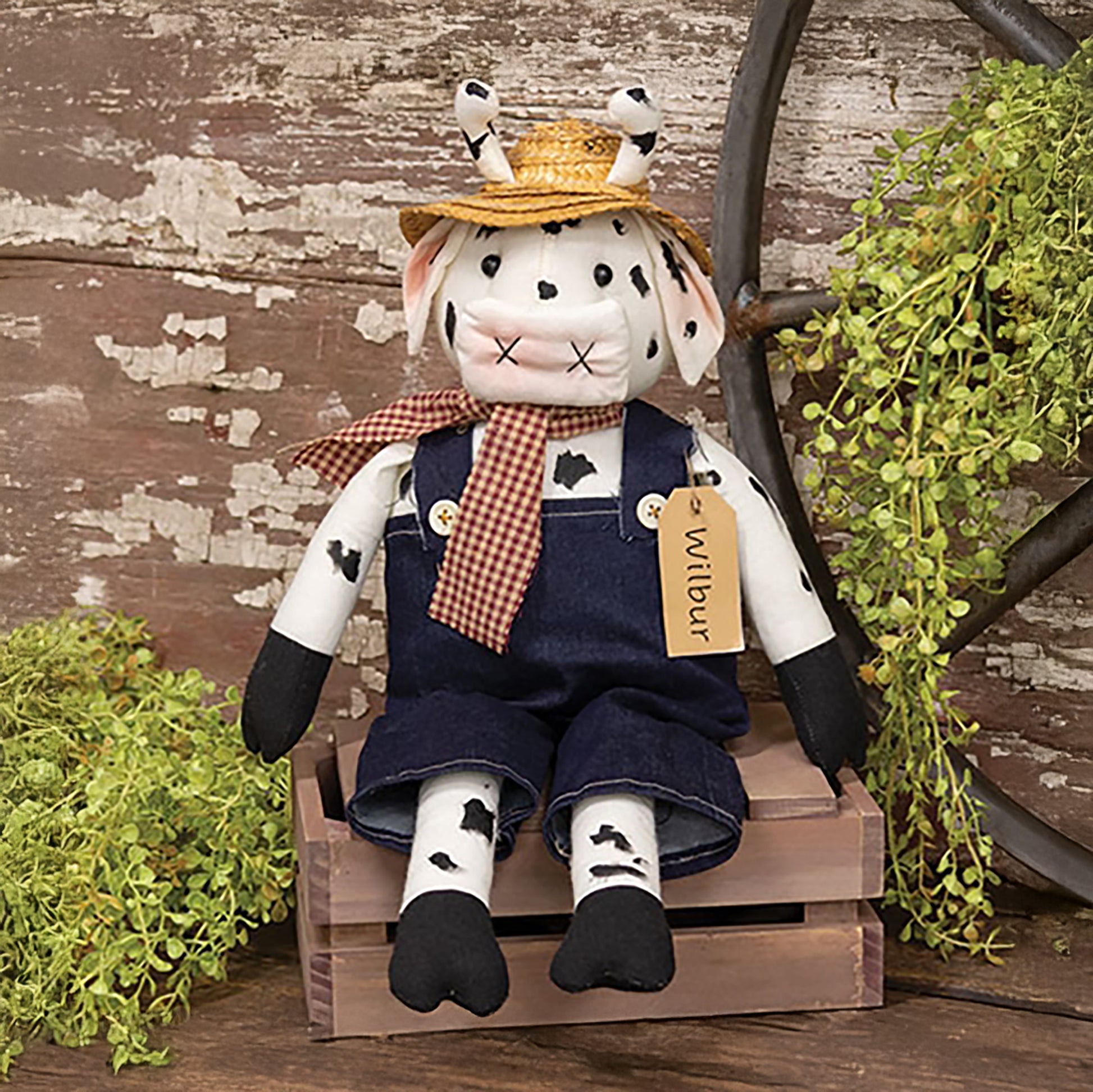 Black and white cow plush doll wearing denim overalls and a red gingham scarf, rustic farmhouse-style home decor