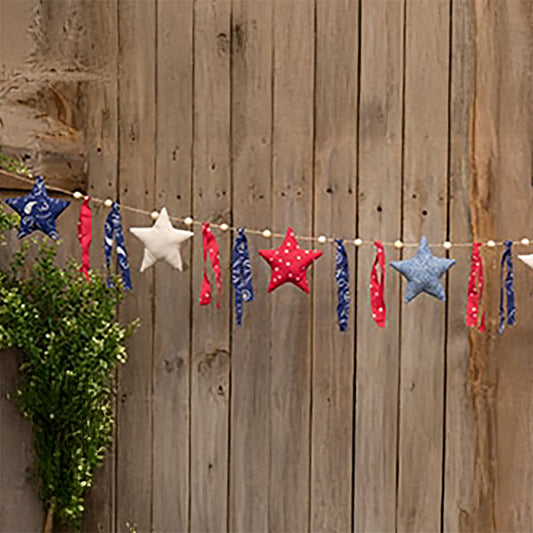 Rustic raggedy star garland with red cream and blue fabric stars hanging on farmhouse mantel with wood bead accents