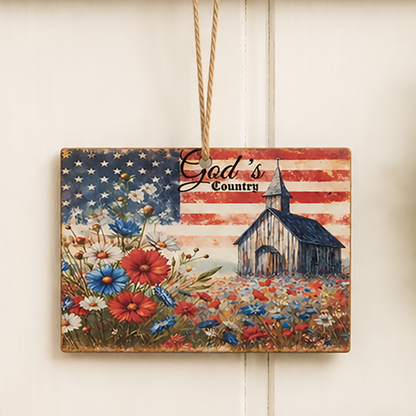 Americana wood ornament featuring weathered barn artwork, American flag background, and "God's Country" sentiment with rustic jute hanger