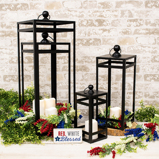 Set of four black metal open air frame lanterns with matte black finish and graduated sizes for farmhouse décor