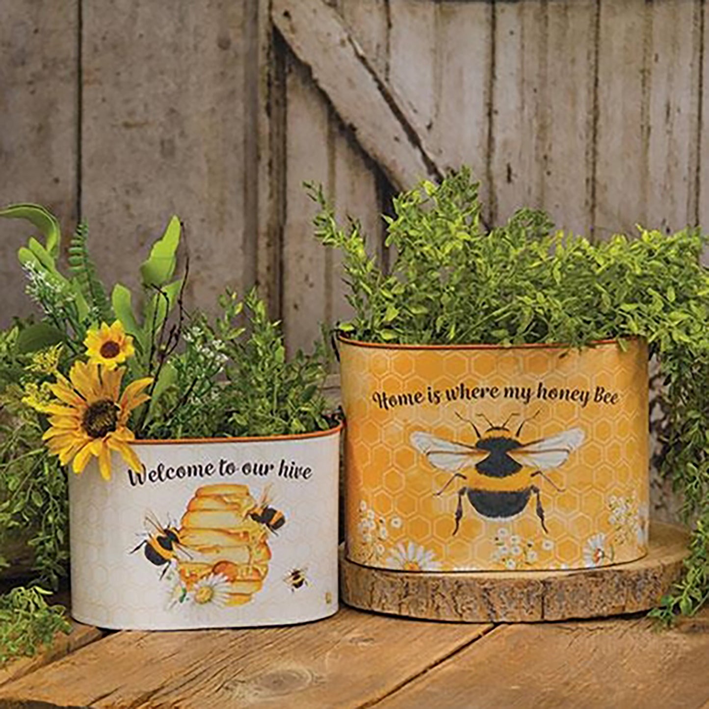 Set of two honey bee-themed oval metal buckets with handles and wooden grips, featuring floral and hive designs