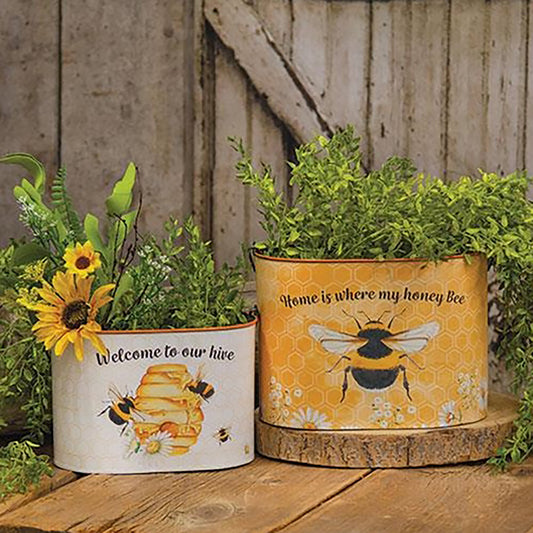 Set of two honey bee-themed oval metal buckets with handles and wooden grips, featuring floral and hive designs