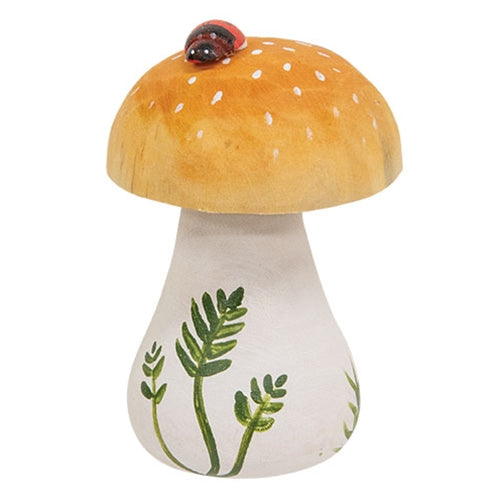 Small carved mushroom figure on tabletop with painted ladybug and rustic color palette