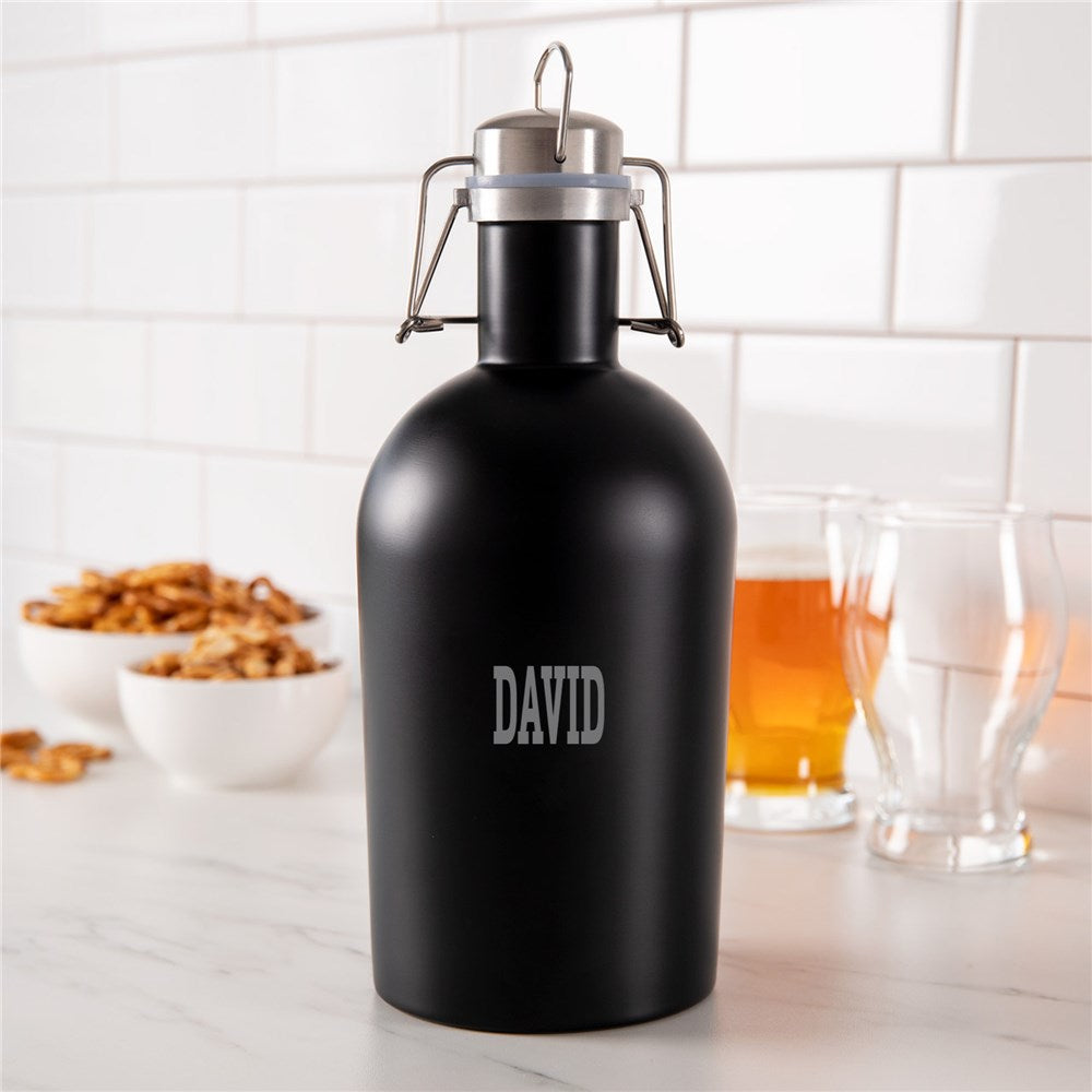 A matte black stainless steel growler with the name 'DAVID' engraved on the front, featuring a swing top lid, handle, and spout, displayed on a kitchen countertop.