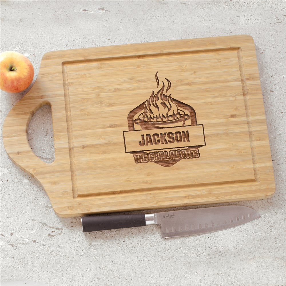 Engraved bamboo cutting board with "The Grill Master" text and personalized name displayed on kitchen counter