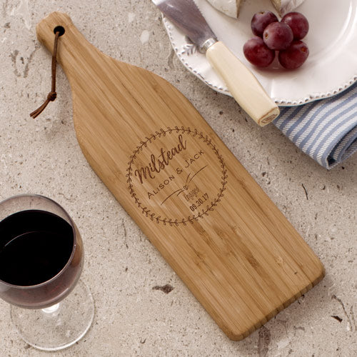 Engraved wine bottle-shaped wooden cutting board with custom text for engaged couple