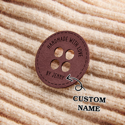 Engraved synthetic leather sewing tags for custom handmade garments, knitwear accessories, and craft fair products.