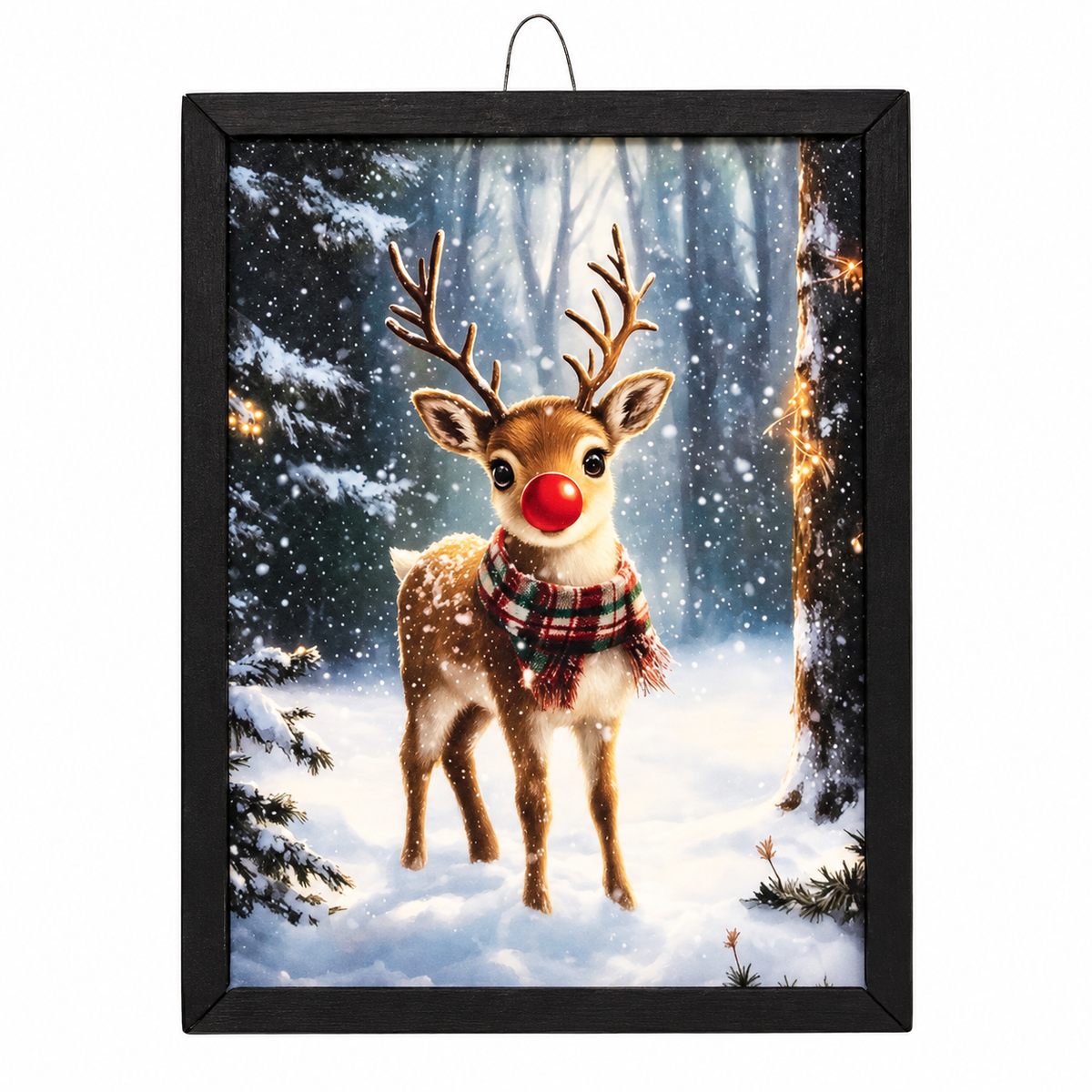 Framed wall art featuring a snowy winter forest scene with a brown reindeer wearing a red nose and plaid scarf, displayed in a black frame against a white background.