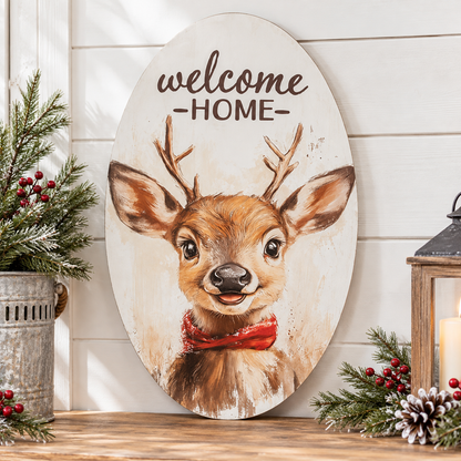 Oval wooden wall sign with a painted deer face and the words “welcome HOME” at the top, displayed on a wooden surface against a white shiplap wall with holiday greenery and a lantern around it.