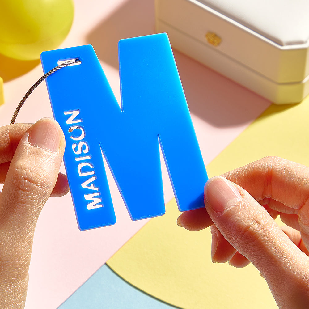 A close-up of hands gently holding the blue letter M, highlighting its 3D printed design.