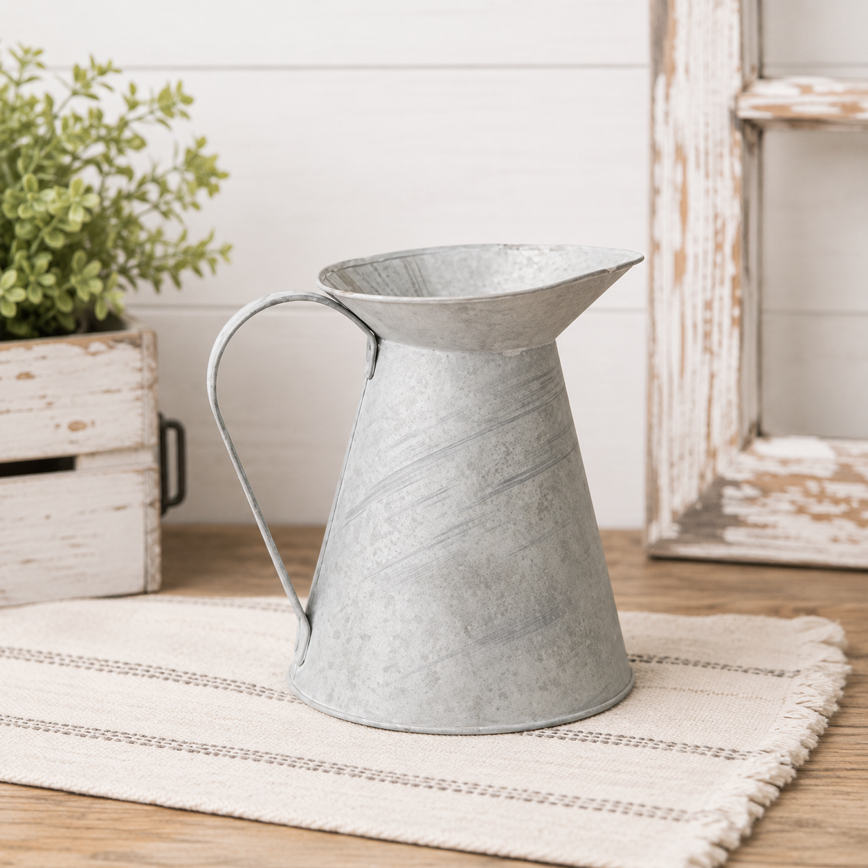 Galvanized zinc metal pitcher with a brushed washed finish, wide opening and rounded handle for floral and greenery displays.