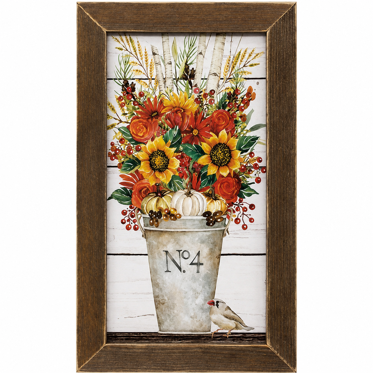 Framed autumn floral wall art featuring a rustic metal bucket filled with sunflowers, pumpkins, orange berries, and wheat on a white wood-plank background, enclosed in a dark brown wooden frame.
