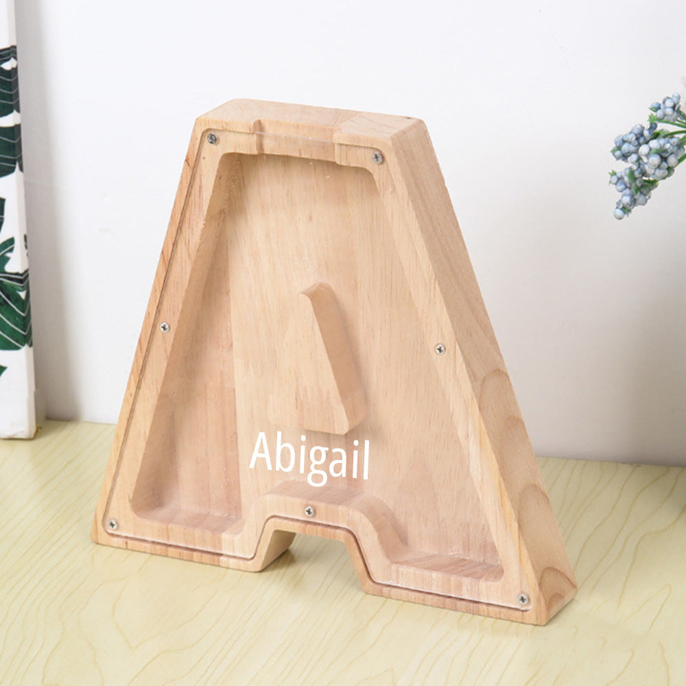 A personalized wooden letter "A" piggy bank with an acrylic front, ideal for kids to save money and observe their savings grow.