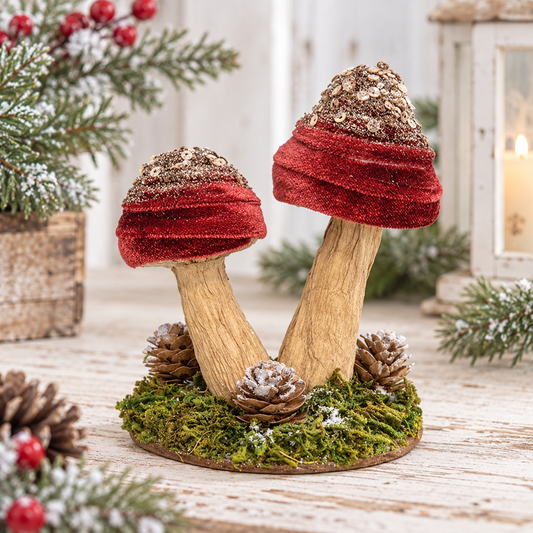 A decorative pair of small mushrooms on a round mossy base, styled with pine branches, pinecones, and a lantern in a rustic indoor setting.
