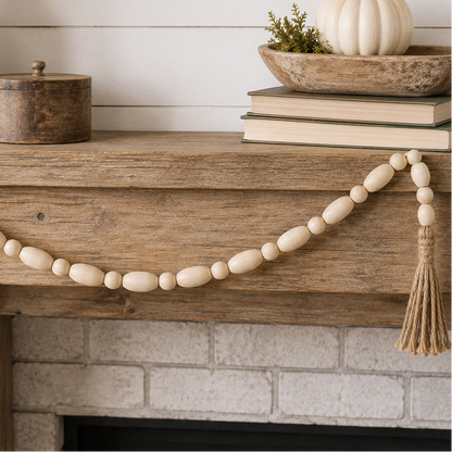 A natural wood bead garland with tassel ends draped across a rustic wooden fireplace mantel in a styled home decor setting.