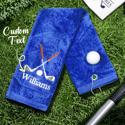 A blue golf towel with the customer's personalized embroidered last name, featuring a sturdy clip for easy attachment to golf bags or backpacks.