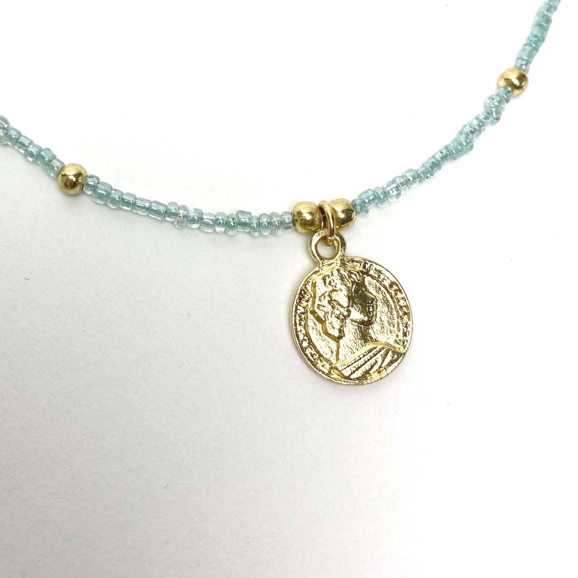 Handmade glass bead necklace featuring brass charm centerpiece