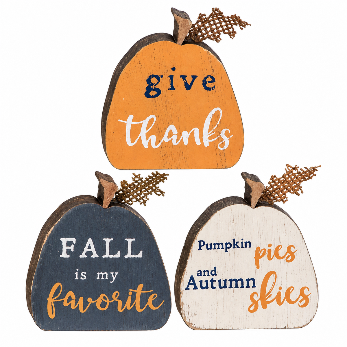 Three rustic wooden pumpkin-shaped signs with autumn-themed phrases: 'give thanks' in orange and white, 'FALL is my favorite' in dark blue and white, and 'Pumpkin pies and autumn skies' in off-white, navy, and orange. The signs are arranged on a plain white background.