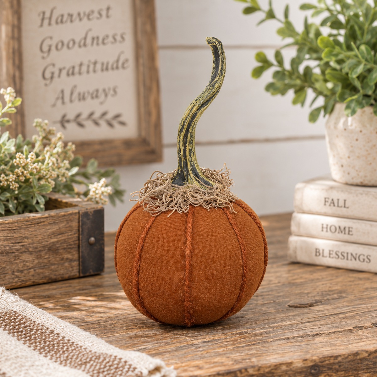 Orange stuffed fabric pumpkin with yarn ribbing, twisted weathered stem, and dried moss accent.