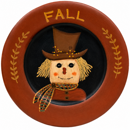 Primitive wooden fall plate with painted scarecrow, plaid scarf, brown leaf accents and the word fall in orange.