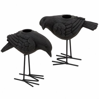 Two black bird-shaped candle holders with textured feathers and thin metal legs, shown on a plain white background.