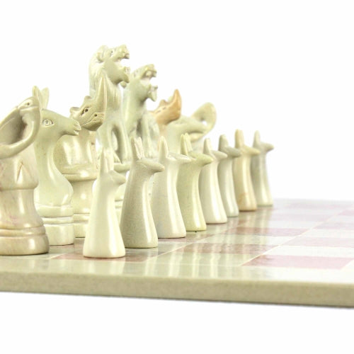 Close-up of intricately carved soapstone chess pieces in natural shades of pink, white, and gold.