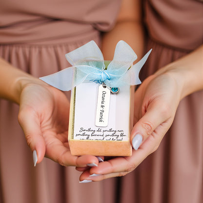 A close-up of the "something blue" charm with a blue ribbon, held by hands, showcasing the personalized detail.